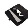 Angled top view of the black SYMA Command demonstrating its storage capacity, with a silver MacBook partially inserted and its front pocket holding a mouse, charger, and cable. Tactical laptop sleeve.