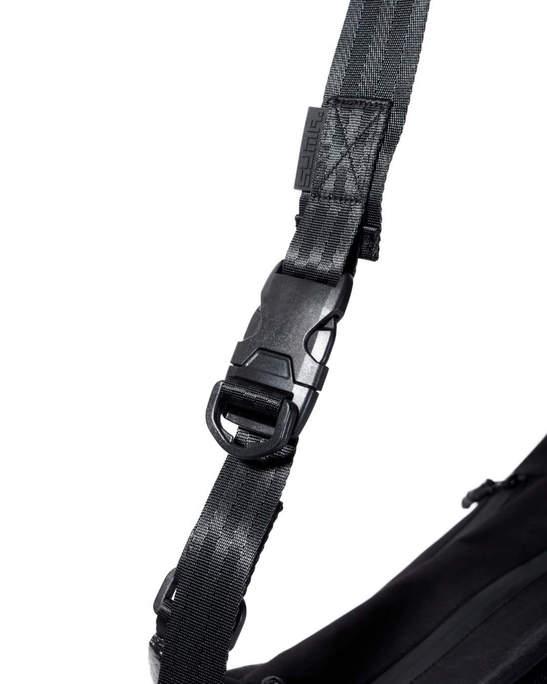 Close-up view of the black SYMA Drone adjustable strap highlighting its heavy-duty quick-release buckle, nylon webbing, and stealth logo tag. Urban sling bag.