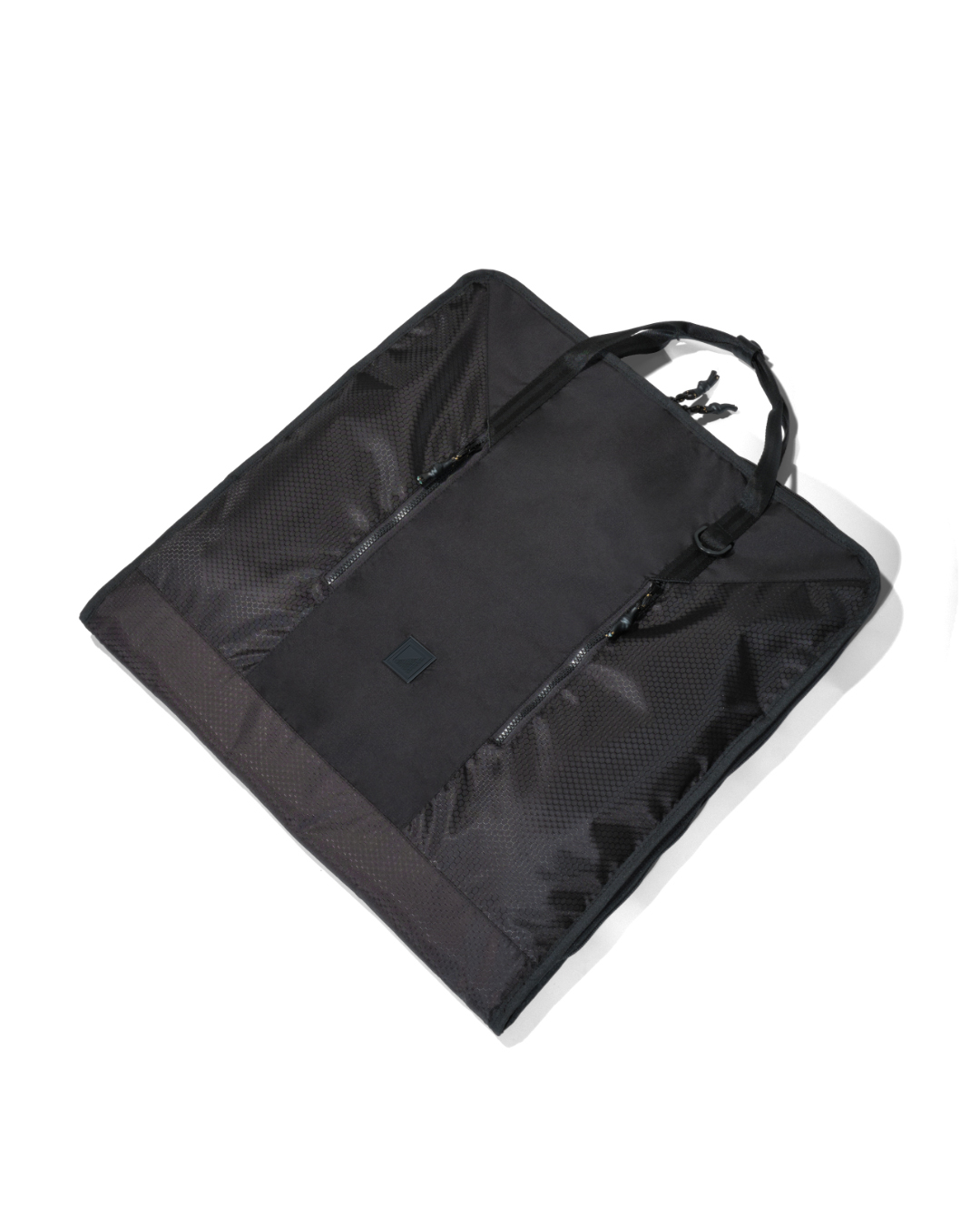 Angled view of the folded black SYMA Motion laid flat, highlighting its durable hexagon ripstop texture, sleek exterior, and top handles. Travel garment bag.