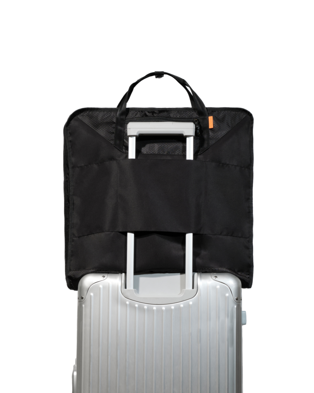 Straight rear view of the folded black SYMA Motion secured to a silver rolling suitcase handle via its luggage slip-through sleeve. Travel garment bag.