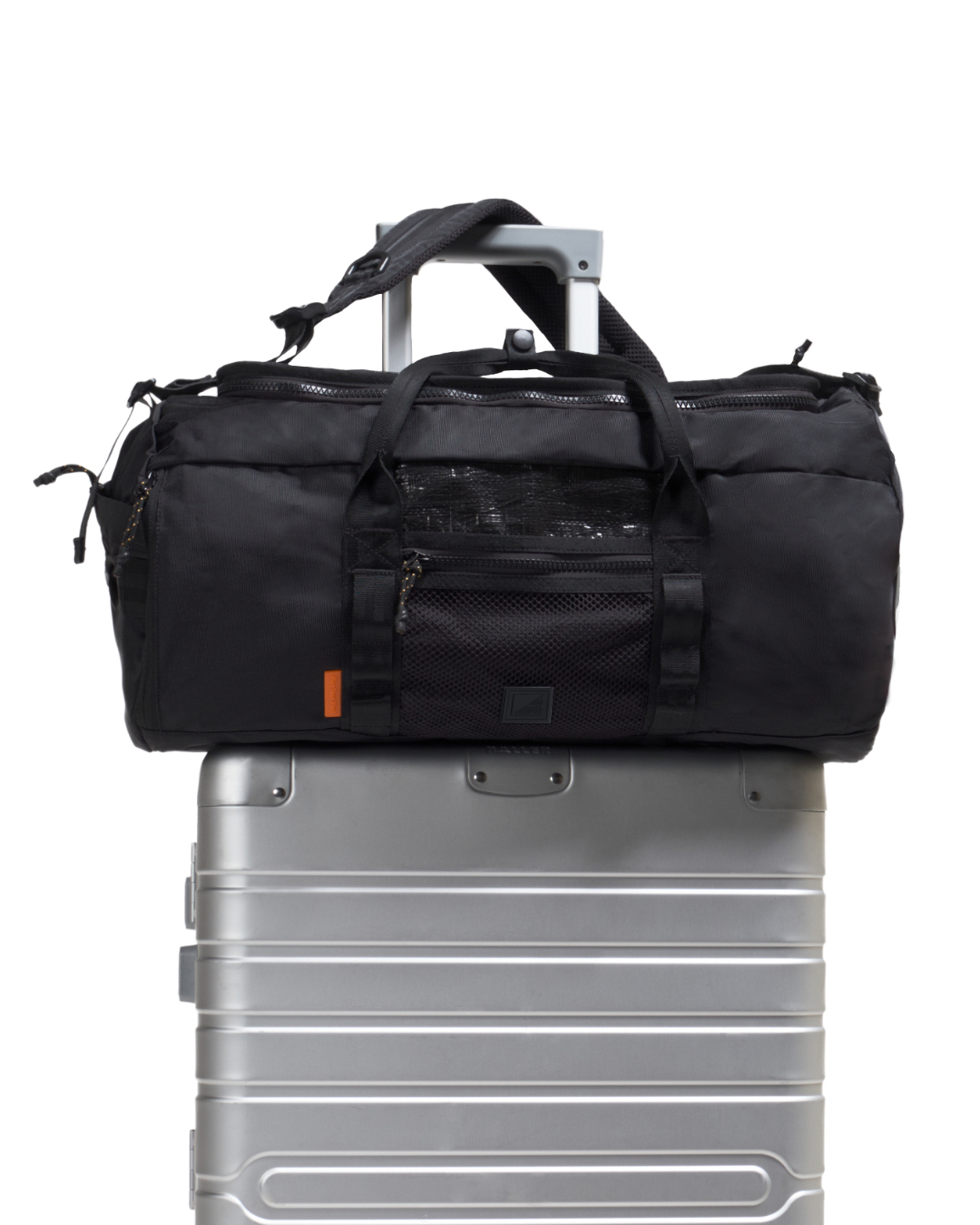 Front view of black SYMA Wonder Duffle Bag resting on top of a silver suitcase, highlighting its front mesh pocket and travel readiness. Versatile weekend duffle bag.