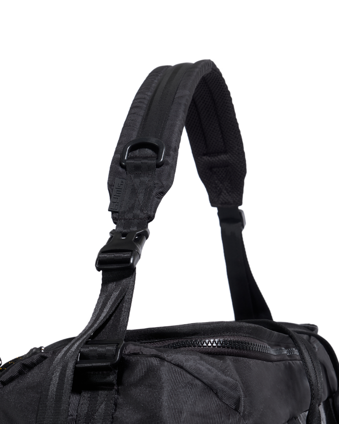 Close-up view of black SYMA Wonder Duffle Bag highlighting thick padded shoulder strap, D-ring, and adjustable buckle. Versatile weekend duffle bag.