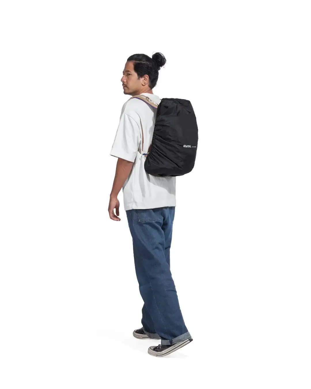 Man in casual outfit walking with his backpack protected by the black SYMA Daytripper. Packable backpack rain cover