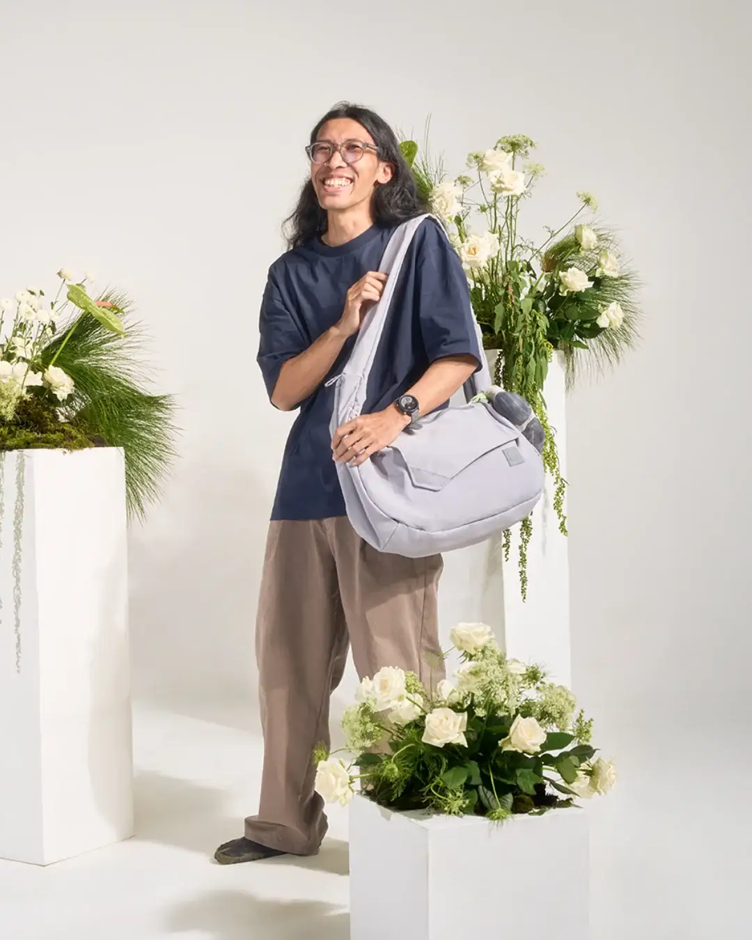 Man wearing SYMA Fable Sling Bag Light Grey on shoulder. 16L minimalist tech messenger