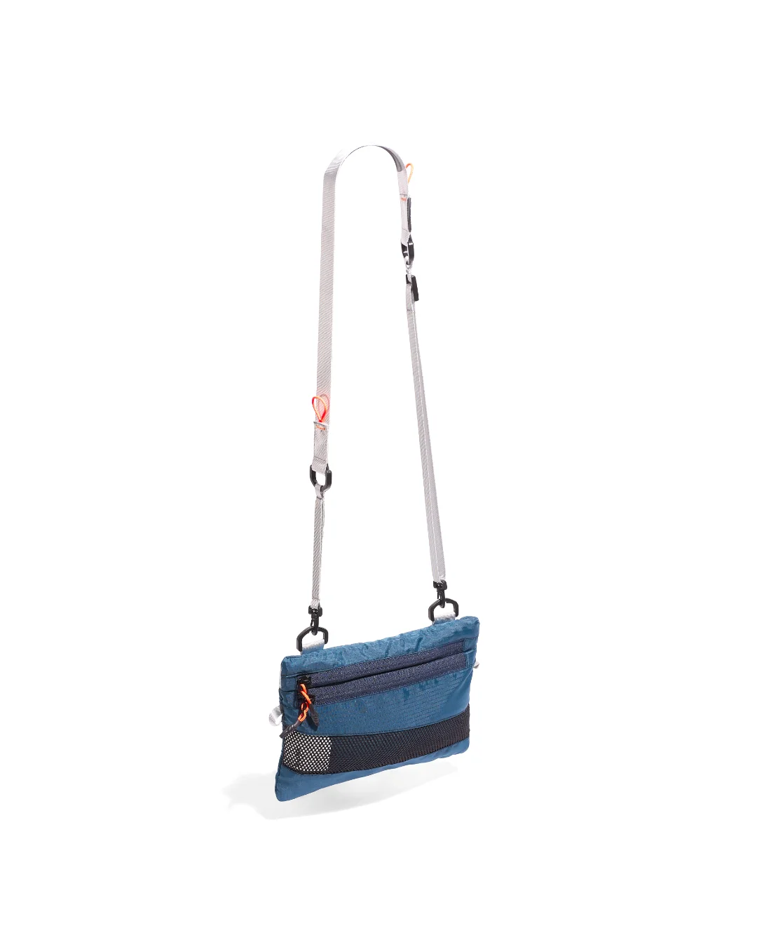 Low-angle three-quarter suspended view of the SYMA Mantra navy sacoche bag, highlighting its durable ripstop body, bottom mesh panel, front zipper compartments with orange pullers, and light gray adjustable strap with black hardware