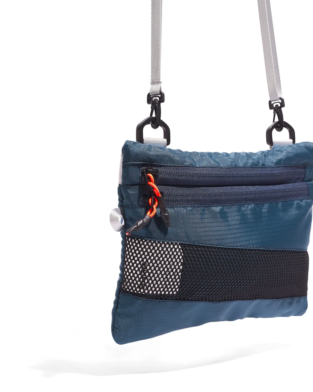 Close-up detail view of the SYMA Mantra navy sacoche bag, highlighting the textured 210D polyester ripstop grid, dual front zippers with custom knotted orange paracord pullers, bottom mesh panel, and black quick-release swivel hardware